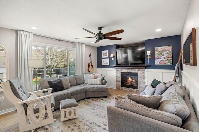 living room featuring a ceiling fan, a glass covered fireplace, wood finished floors, and recessed lighting