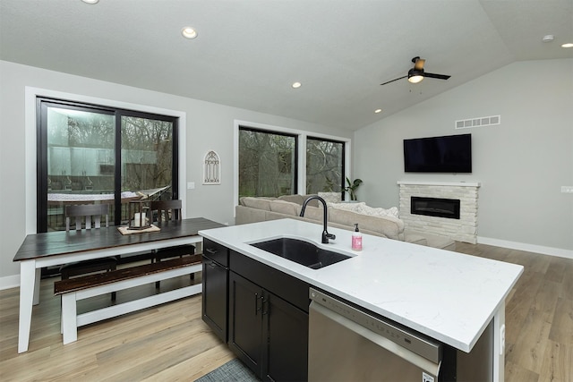 1040 W Trace Pl, Polk City, IA 50226 - kitchen featuring vaulted ceiling, stainless steel dishwasher, a sink, a fireplace, and open floor plan