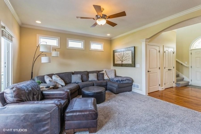 living room with stairway, visible vents, crown molding, and ceiling fan