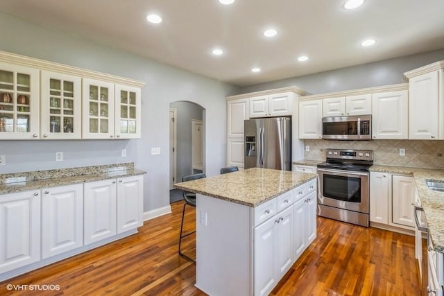 kitchen featuring arched walkways, white cabinets, appliances with stainless steel finishes, dark wood-type flooring, and recessed lighting