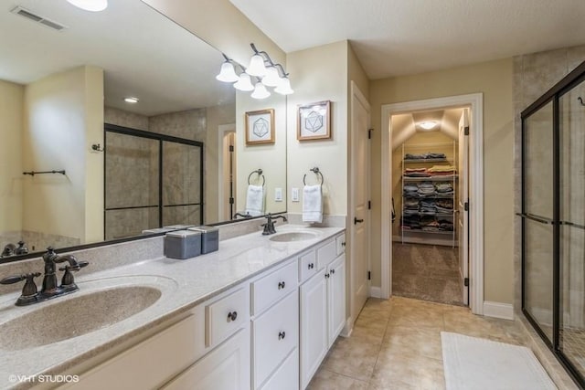 bathroom featuring a walk in closet, visible vents, a stall shower, and a sink