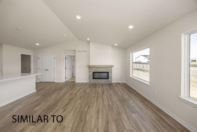 16514 Ironwood Ln, Urbandale, IA 50323 - unfurnished living room with lofted ceiling, healthy amount of natural light, light wood finished floors, a fireplace, and baseboards