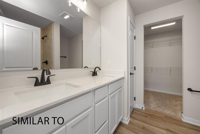 16514 Ironwood Ln, Urbandale, IA 50323 - full bathroom featuring a spacious closet, a shower, double vanity, wood finished floors, and baseboards
