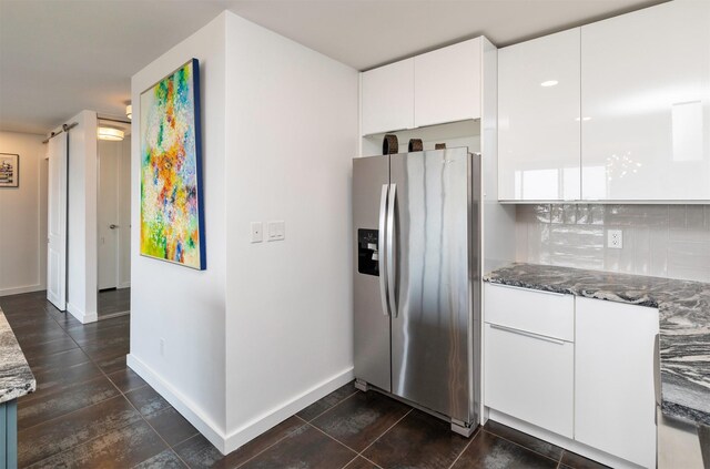 3663 Grand Ave Unit 905, Des Moines, IA 50312 - kitchen with dark stone countertops, decorative backsplash, baseboards, white cabinets, and stainless steel refrigerator with ice dispenser