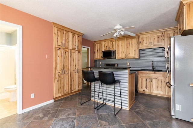 kitchen featuring dark countertops, appliances with stainless steel finishes, ceiling fan, and a sink