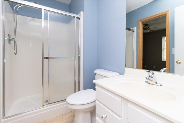 bathroom featuring a stall shower, ceiling fan, toilet, and vanity