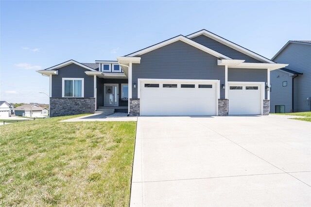 view of front of property with concrete driveway, an attached garage, stone siding, and a front lawn