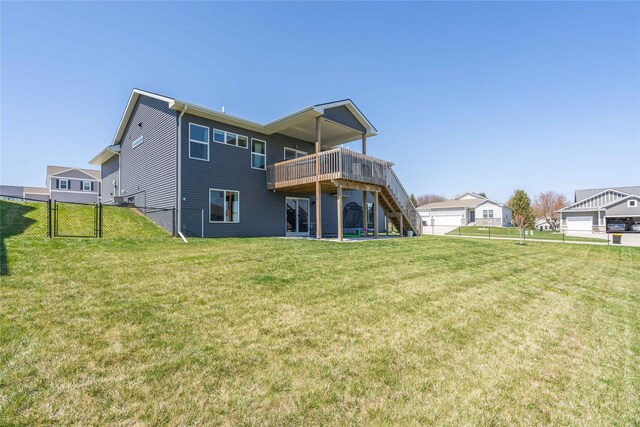 rear view of house featuring a gate, fence, a wooden deck, a lawn, and stairway