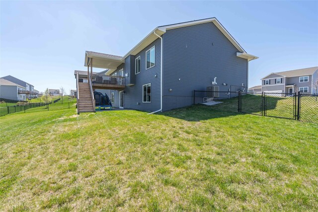 back of house featuring a fenced backyard, a gate, a wooden deck, stairs, and a yard