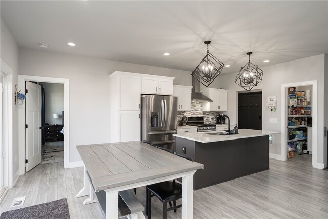kitchen with recessed lighting, wall chimney exhaust hood, stainless steel appliances, and a sink