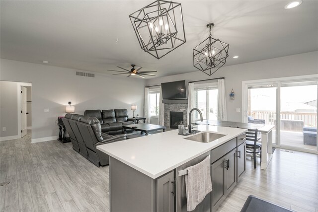 kitchen with a sink, visible vents, gray cabinets, dishwasher, and a fireplace