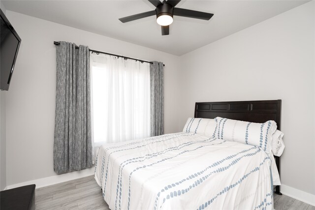 bedroom featuring wood finished floors, a ceiling fan, and baseboards