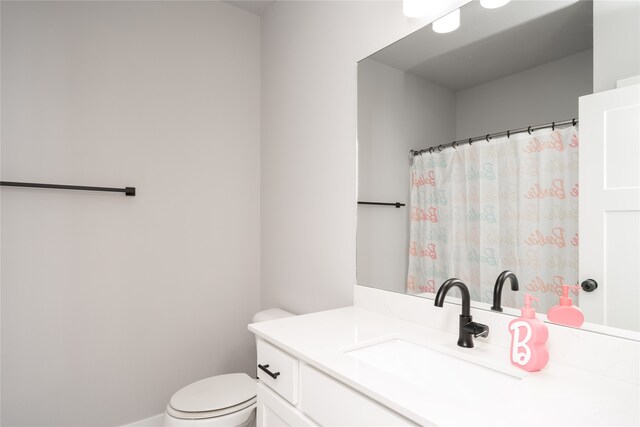 bathroom featuring toilet, vanity, curtained shower, and baseboards