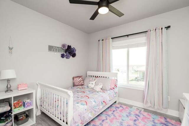 bedroom featuring wood finished floors, visible vents, a ceiling fan, and baseboards
