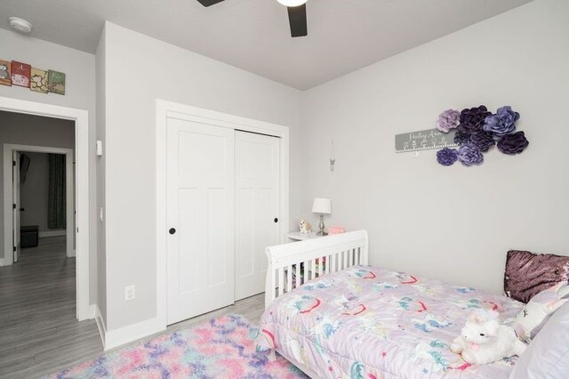 bedroom with baseboards, wood finished floors, a closet, and ceiling fan