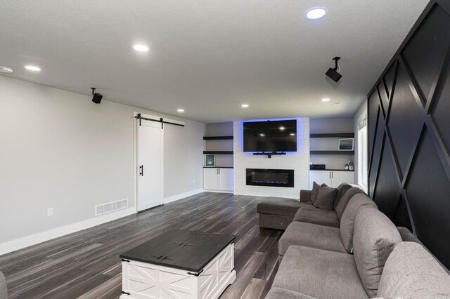 living room featuring a barn door, baseboards, dark wood-type flooring, and visible vents