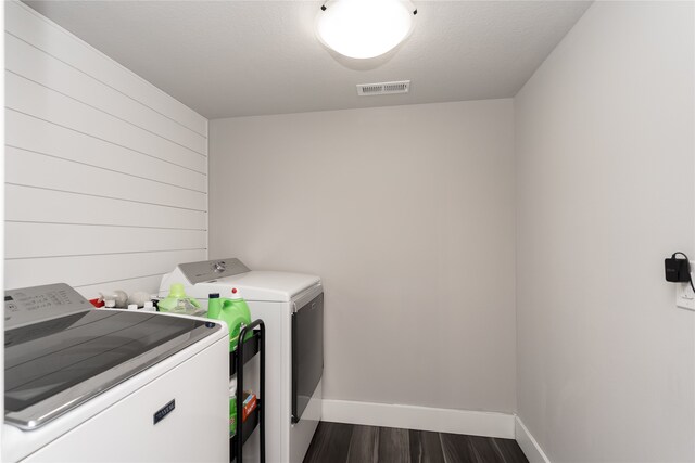 clothes washing area featuring separate washer and dryer, laundry area, dark wood finished floors, baseboards, and visible vents