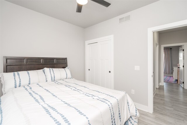 bedroom with wood finished floors, a closet, ceiling fan, baseboards, and visible vents