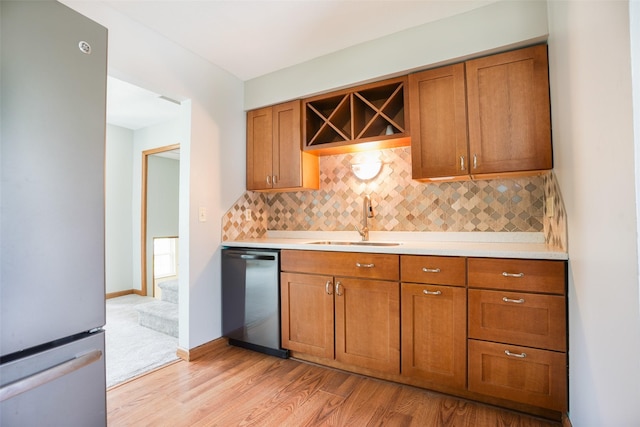 kitchen featuring dishwasher, brown cabinets, a sink, and freestanding refrigerator