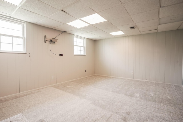 basement with carpet, visible vents, and a drop ceiling