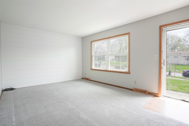carpeted spare room featuring baseboards and visible vents