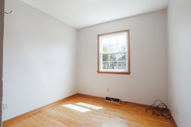 unfurnished room with light wood finished floors, baseboards, and visible vents