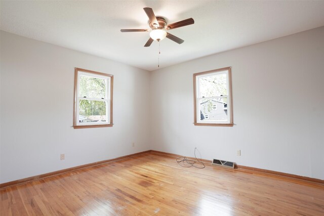 empty room featuring baseboards, a ceiling fan, visible vents, and light wood-type flooring