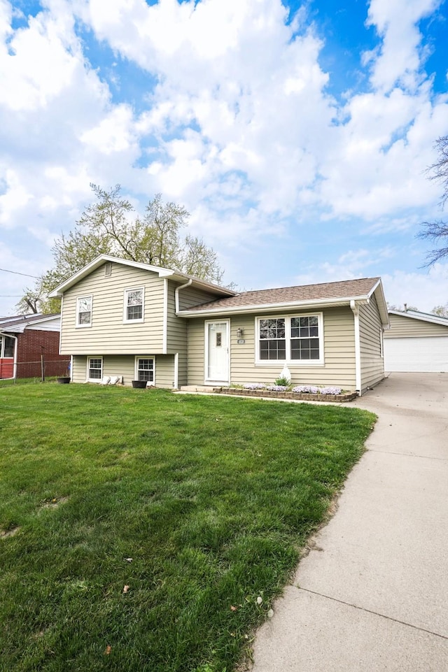 tri-level home featuring an outbuilding, a front yard, fence, and driveway