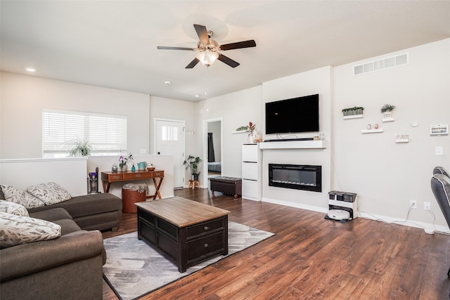 2802 SW Prairie Trail Pkwy, Ankeny, IA 50023 - living area featuring visible vents, a glass covered fireplace, baseboards, a ceiling fan, and wood finished floors