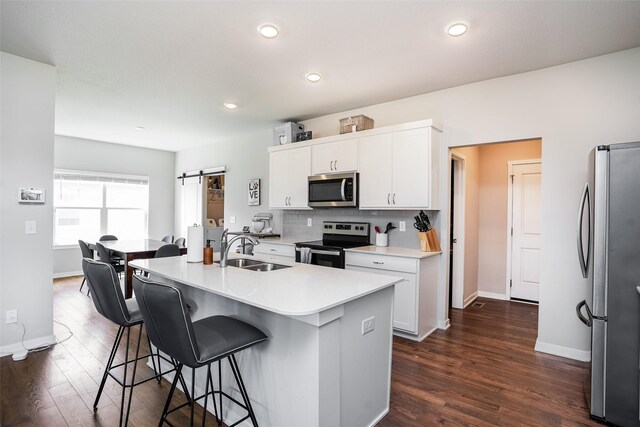2802 SW Prairie Trail Pkwy, Ankeny, IA 50023 - kitchen with a sink, dark wood-style flooring, appliances with stainless steel finishes, a breakfast bar area, and white cabinetry