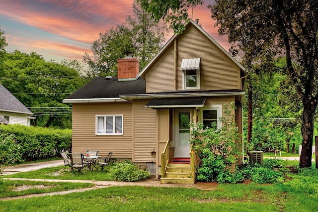 back of house with a chimney and a yard
