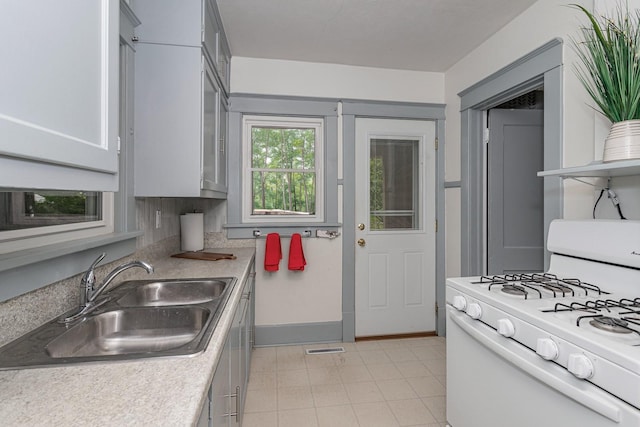 kitchen with a sink, visible vents, light countertops, white range with gas cooktop, and baseboards