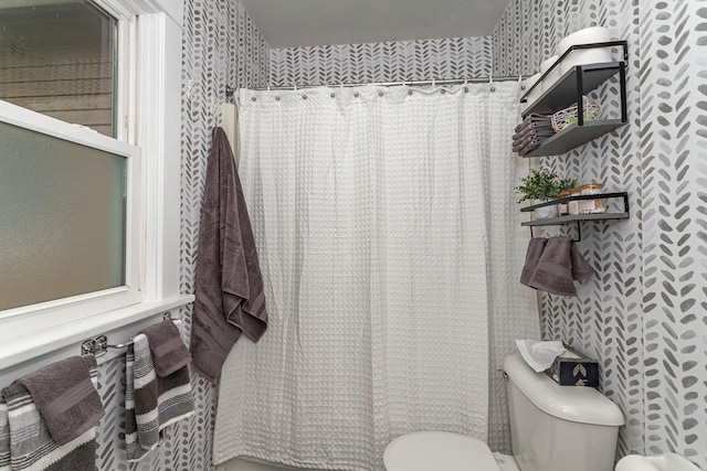 bathroom featuring wallpapered walls, toilet, and curtained shower