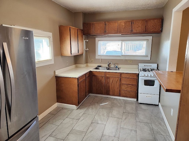 946 Miller Ave, Iowa City, IA 52246 - kitchen with white gas range oven, brown cabinets, a sink, light countertops, and freestanding refrigerator