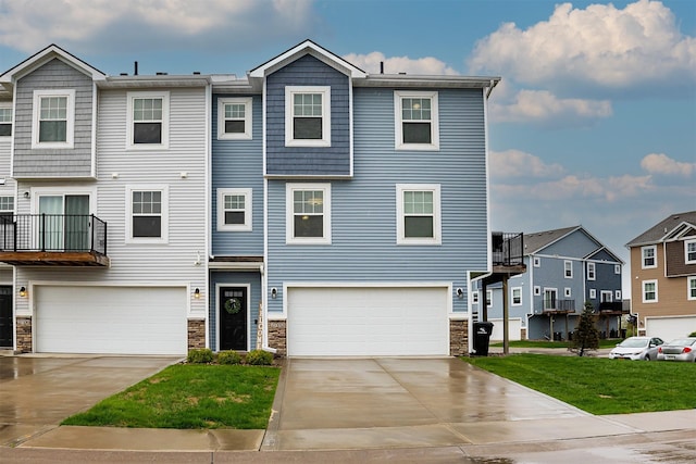 view of property featuring a residential view, driveway, stone siding, and an attached garage