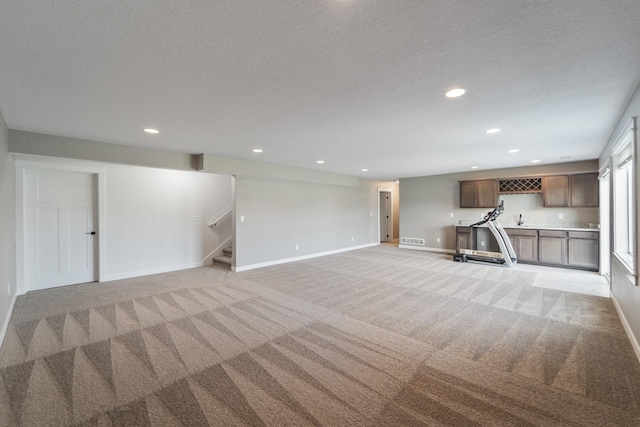 basement with baseboards, recessed lighting, stairs, and light colored carpet