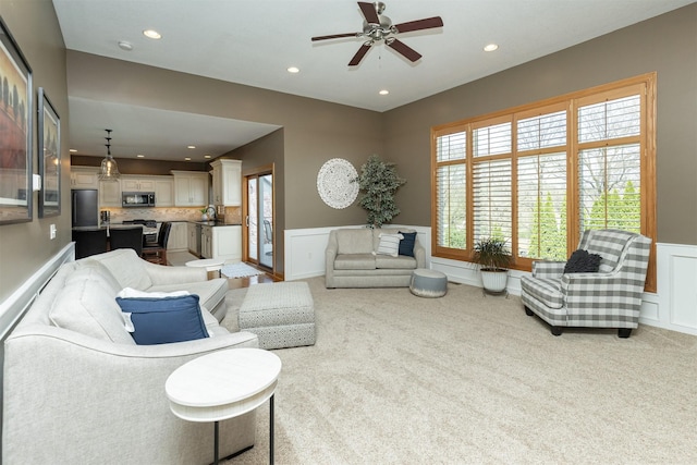 carpeted living room with a wealth of natural light, ceiling fan, recessed lighting, and wainscoting