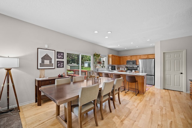 dining room featuring baseboards, recessed lighting, light wood-style floors, and a textured ceiling