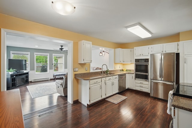 kitchen featuring a baseboard heating unit, a sink, stainless steel appliances, a warming drawer, and white cabinets