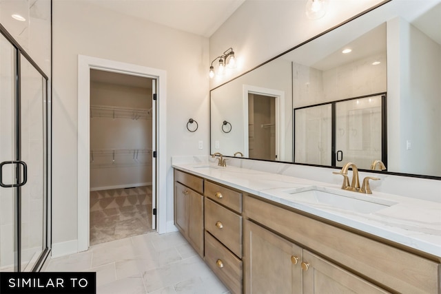 full bathroom with double vanity, a walk in closet, a stall shower, and a sink