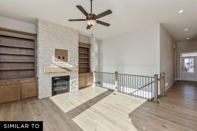 unfurnished living room featuring baseboards, recessed lighting, a fireplace, wood finished floors, and a ceiling fan