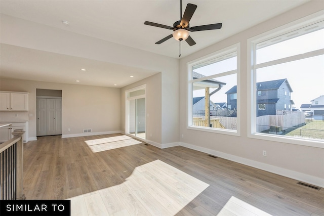 unfurnished living room with baseboards, visible vents, light wood-type flooring, and ceiling fan