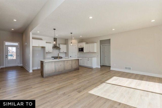kitchen with baseboards, recessed lighting, wall chimney exhaust hood, and white cabinetry