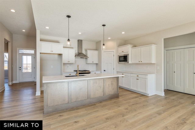 kitchen with white cabinetry, backsplash, wall chimney exhaust hood, and a sink