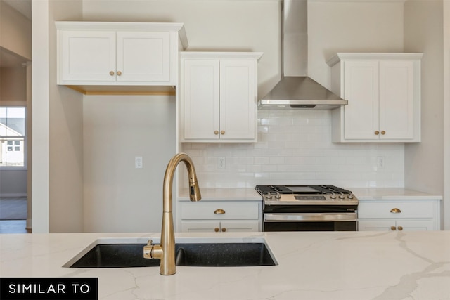 kitchen with light stone countertops, a sink, tasteful backsplash, wall chimney exhaust hood, and gas stove