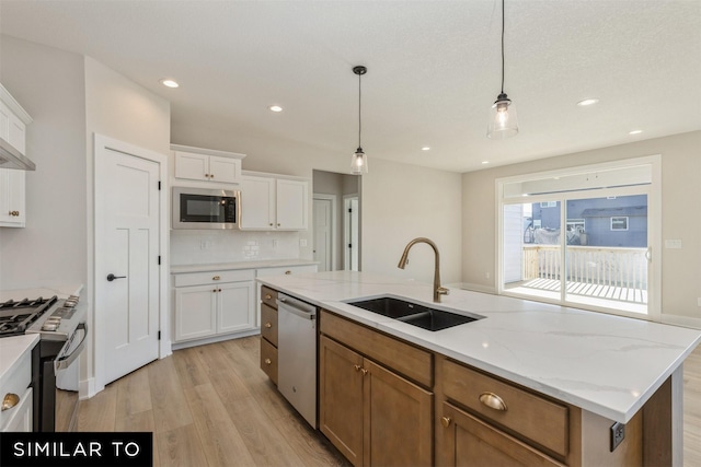 kitchen with tasteful backsplash, white cabinets, light wood-style flooring, a sink, and stainless steel appliances