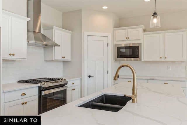 kitchen with gas stove, a sink, white cabinetry, built in microwave, and wall chimney exhaust hood
