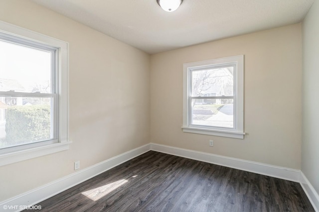 spare room featuring dark wood-style floors, a wealth of natural light, and baseboards