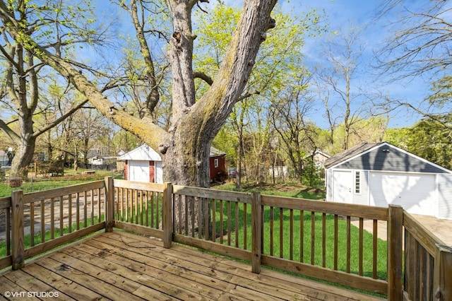 wooden terrace featuring a garage, an outbuilding, and a yard