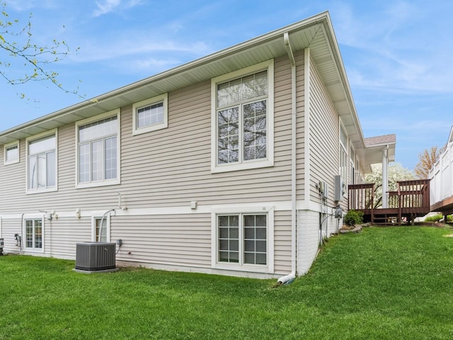 rear view of property with a deck, a yard, and central AC